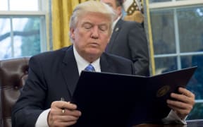 US President Donald Trump reads an executive order withdrawing the US from the Trans-Pacific Partnership prior to signing it in the Oval Office of the White House.