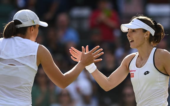 Poland's Iga Swiatek (L) shakes hands with France's Alize Cornet after their women's singles tennis match on the sixth day of the 2022 Wimbledon Championship at The All England Tennis Club in Wimbledon, south-west London, on July 2, 2022. (Photo by Glyn KIRK / AFP) / RESTRICTED FOR EDITORIAL USE