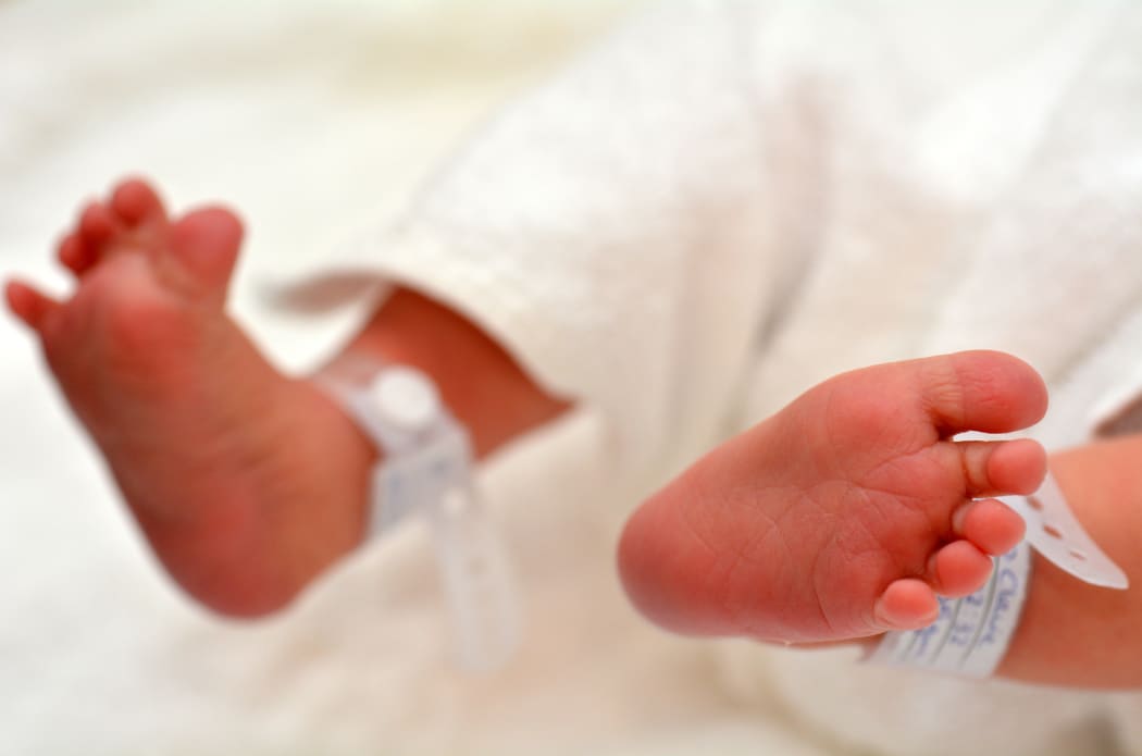 Newborn baby feet with identification bracelet tag name.