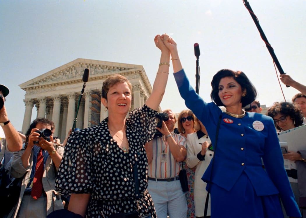 Norma McCorvey, Jane Roe in the 1973 court case (left) and attorney Gloria Allred (right) hold hands as they leave the Supreme Court building in Washington on April 26, 1989, after sitting in court listening to arguments in a Missouri abortion case.
