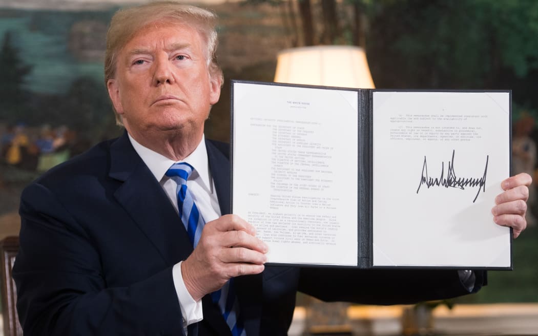 In this file photo taken in May 2018 US President Donald Trump signs a document reinstating sanctions against Iran