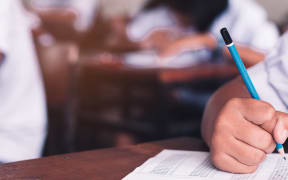 Exam with uniform school student doing educational test with stress in classroom.16:9 style
