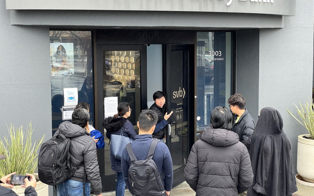 A worker (centre) tells people that the Silicon Valley Bank (SVB) headquarters is closed on 10 March, 2023 in Santa Clara, California.