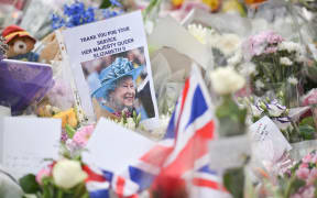 A portrait of Britain's Queen Elizabeth II is seen amongst flowers put down by well-wishers outside of Buckingham Palace in London on September 10, 2022, two days after she died at the age of 96. - King Charles III pledged to follow his mother's example of "lifelong service" in his inaugural address to Britain and the Commonwealth on Friday, after ascending to the throne following the death of Queen Elizabeth II on September 8. (Photo by LOIC VENANCE / AFP)