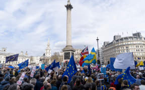 People hold up placards and European Union flags as they pass Trafalgar Square on a march and rally organised by the pro-European People's Vote campaign for a second EU referendum in central London on March 23, 2019.