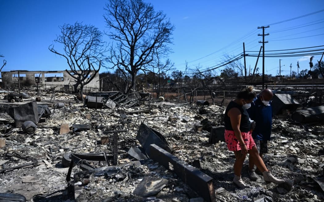 Lahaina residents look for belongings inthe ashes of their family’s home.