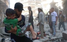 A man carries an injured child as the civil defense workers and civilians evacuate the wounded people and dead bodies pulled from the debris after Russian forces staged air-strike over residential areas in Bustan al Qasr Neighborhood of Aleppo, Syria on April 22, 2016.