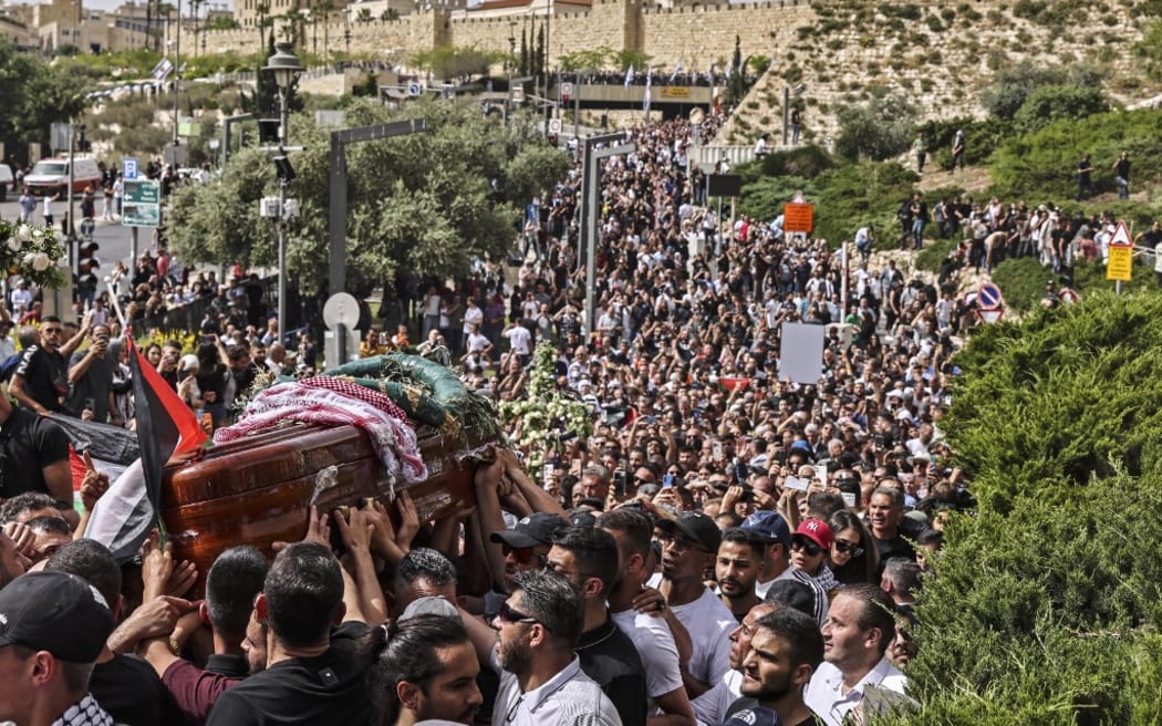 Palestinian mourners carry the casket of slain  Al-Jazeera journalist Shireen Abu Akleh from a church toward the cemetary, during her funeral procession in Jerusalem, on May 13, 2022. - Abu Akleh, who was shot dead on May 11, 2022 while covering a raid in the Israeli-occupied West Bank, was among Arab media's most prominent figures and widely hailed for her bravery and professionalism. (Photo by RONALDO SCHEMIDT / AFP)