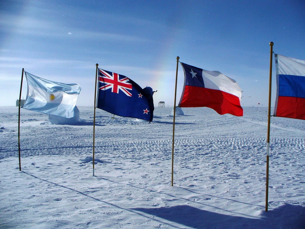 Flags of Argentina, New Zealand, Chile, and Russia at the ceremonial South Pole, with sundog. Amundsen-Scott South Pole Station, Jan. 14, 2010.