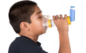 A child users an asthma inhaler.