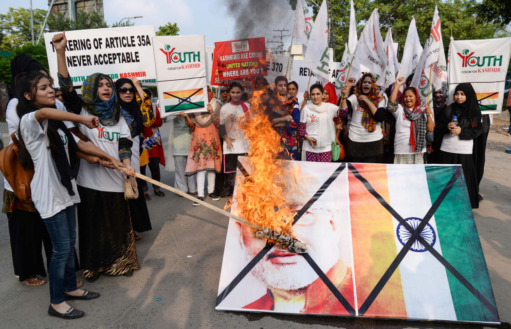 Activists of the Youth Forum for Kashmir group shout slogans as they burn a picture of Indian Prime Minister Narendra Modi and the Indian flag during a protest in Lahore.