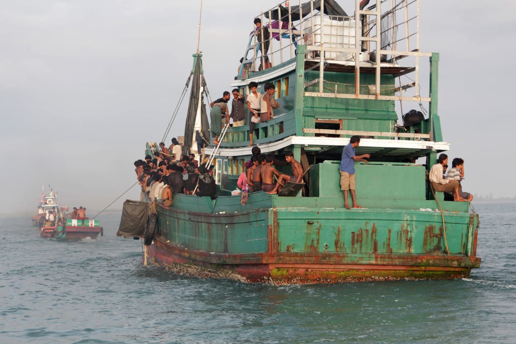 Fishermen help rescue a boat of Rohingya migrants off the coast of Indonesia's East Aceh on 20 May 2015.