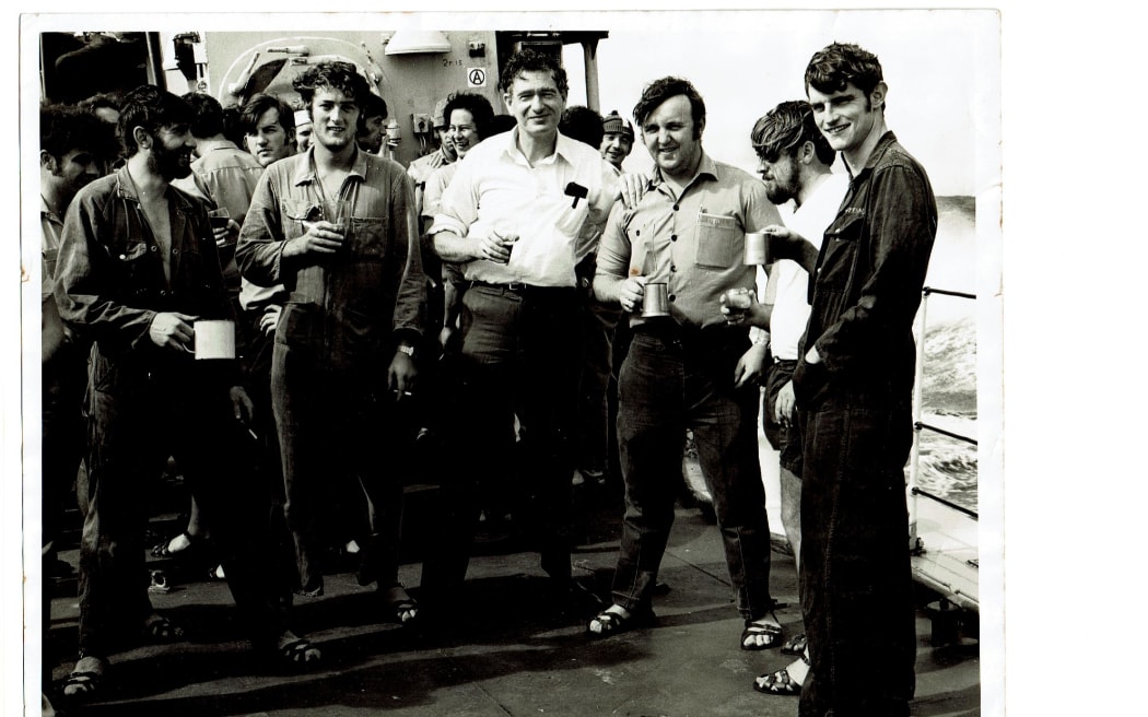 Cabinet minister Fraser Colman has his daily tot of rum aboard Otago. Tony Cox is standing next to him, on the left.