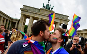 Two men kiss as they attend a rally of gays and lesbians in front of the Brandenburg Gate in Berlin on 30 June, 2017.