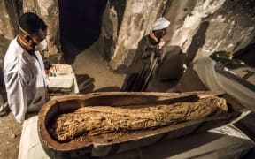 November 24, 2018: Egyptian workers and archaeologists standing next to an opened intact sarcophagus containing a well-preserved mummy of a woman named "Thuya", discovered at Al-Assasif necropolis in Luxor, Egypt