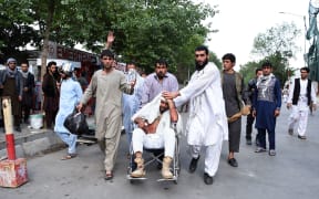 Afghan relatives push the wheelchair of a wounded man outside an Italian aid organisation's hospital after suicide blasts targeted the funeral of a politician's son.