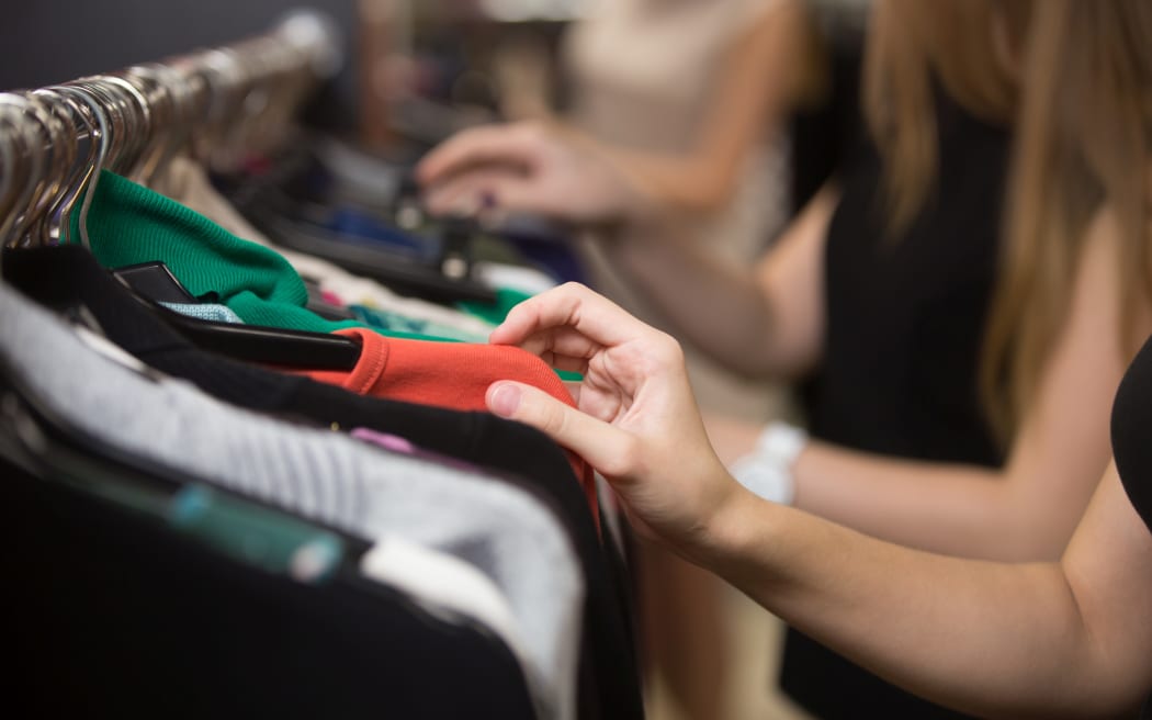 Shoppers looking at a rail of clothes in a mall (Stock photo).