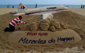 Indian sand artist Sudersan Pattnaik gives final touches to a sand sculpture with a message of prayers for missing Malaysian Airlines flight MH370.