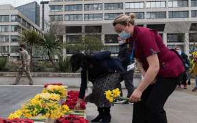 NHS staff lay flowers outside St. Thomas's hospital in central London to remember those who have died from the Coronavirus as part of the National Day of Reflection held one year since lockdown.