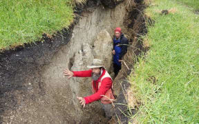 Two geologists standing in a trench
