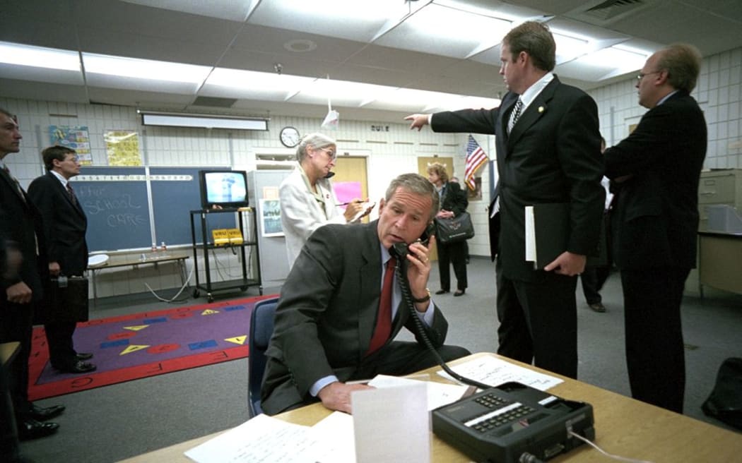Director of Communications Dan Bartlett points to news footage of the World Trade Center Towers burning, September 11, 2001, as President George W. Bush gathers information about the attack from Emma E. Booker Elementary School in Sarasota, Florida.