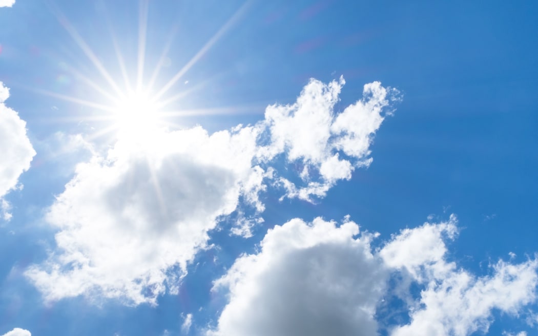 Looking up at Nice blue sky with sun beam behind big cloud.