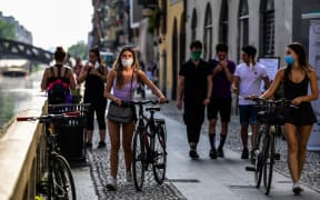 People stroll along the Navigli canals in Milan on May 8, 2020 during the country's lockdown aimed at curbing the spread of the COVID-19 infection, caused by the novel coronavirus.