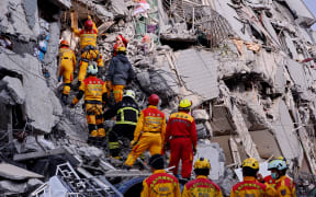 Rescuers try to look for victims at the site where a building collapsed during an earthquake in Tainan.