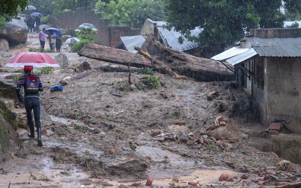 People walk between washed away structures in Blantyre on March 14, 2023, caused by heavy rains following cyclone Freddy's landfall. - Cyclone Freddy, packing powerful winds and torrential rain, killed more than 100 people in Malawi and Mozambique on its return to southern Africa's mainland, authorities said on March 13, 2023.