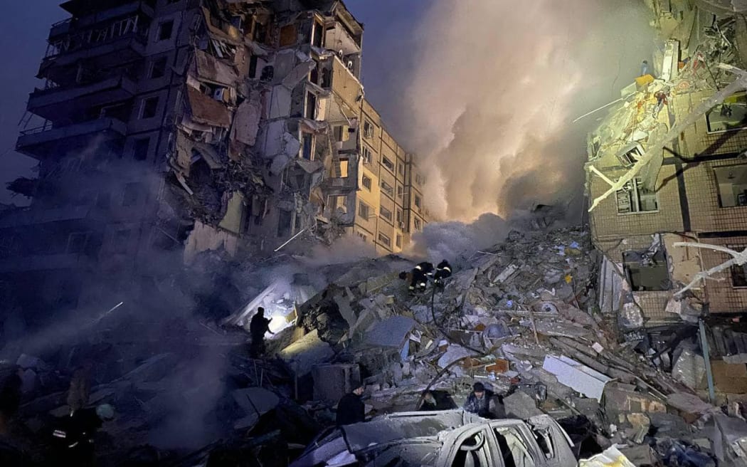 This handout picture taken and released by the Ukrainian Emergency Service on January 14, 2023, shows rescuers working on a residential building destroyed after a missile strike, in Dnipro. - A strike on a residential building in the eastern Ukrainian city of Dnipro on January 14, 2023, left at least five dead and 27 injured, officials said.