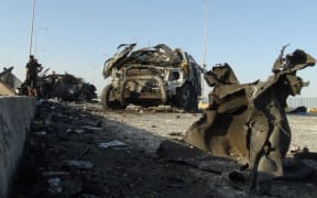 Iraqi security forces and gunmen inspect the wreckage of cars following a suicide bomb attack in Ramadi, the capital of the western province of Anbar.