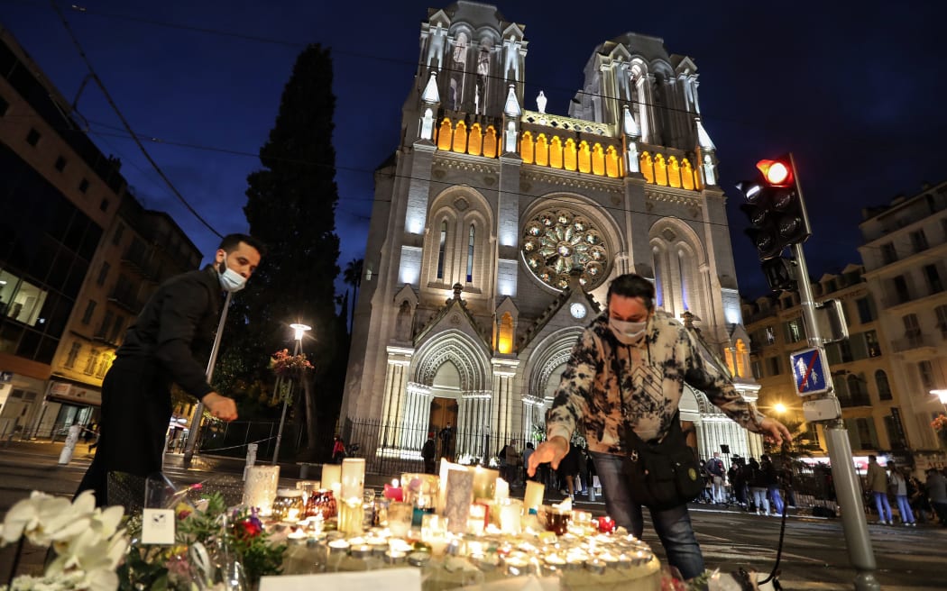 People lights candle outside the Notre-Dame de l'Assomption Basilica in Nice on October 30, 2020, a day after a knife attacker killed three people,