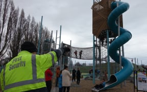 A security guard watches over children at Margaret Mahy Playground.