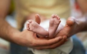 A father holds his child's feet (file)