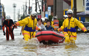 Rescue workers transport evacuees in a rubber boat through floodwaters.