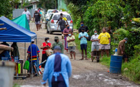 Residents look on as police check people are wearing face masks in Suva.