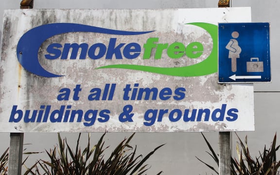 A dirty-looking Smokefree sign. It reads "SMOKEFREE - AT ALL TIMES - BUILDINGS & GROUNDS"