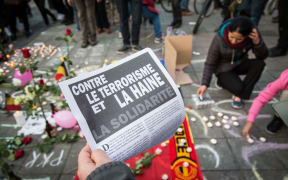 A man holds a flyer reading 'Against terrorism and hate' at a makeshift memorial in front of the stock exchange at the Place de la Bourse (Beursplein) in Brussels