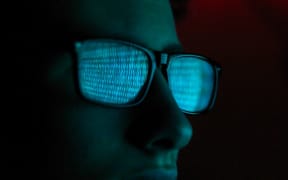 Cyber Crime, reflection in spectacles of virus hacking a computer, close up of face (Photo by Andrew Brookes / Cultura Creative / Cultura Creative via AFP)