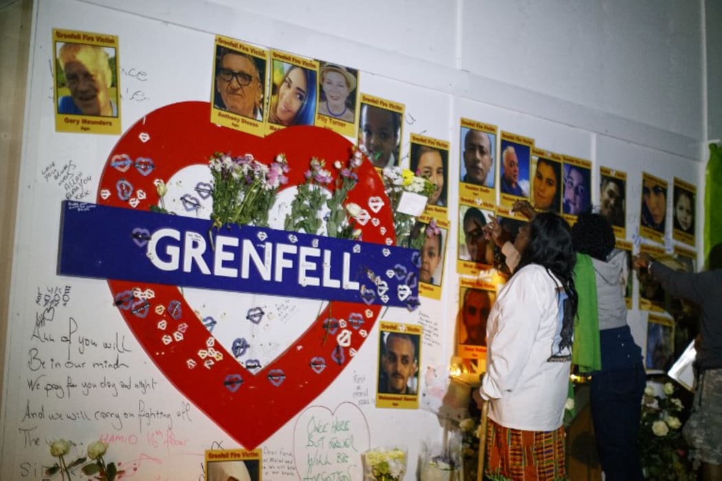 People look at pictures of the victims as members of the public hold a vigil and commemoration near Grenfell Tower in west London at midnight June 14, 2018 to honour the 71 people who died when a fire ripped through the Grenfell tower block in London one year ago.