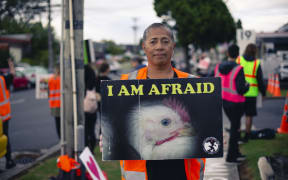 Leona Tavui holds a protest sign at an Auckland Save Movement Vigil outside Tegel in Henderson.