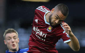 All White Winston Reid in action for West Ham twists to successfully head the ball.