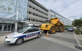 truck is parked behind a police vehicle outside the local government building as part of a protest in Noumea organised by ContraKmine, the union of mining contractors, calling on local authorities to overturn a decision on nickel exports to China on August 5, 2015.