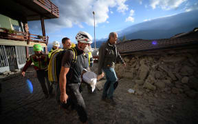 Rescuers carry an injured man among damaged homes after a strong heathquake hit Amatrice