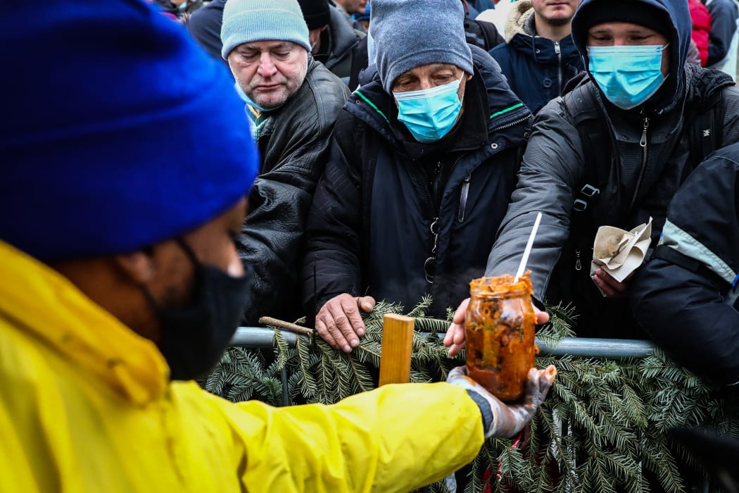 Homeless people in Krakow, Poland battle the winter cold to claim cabbage stew given out by a restaurant on 19 December.