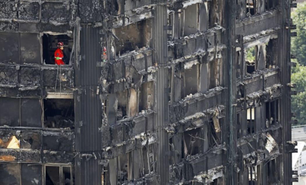 Members of the emergency services work on the middle floors of the charred remnains of the Grenfell Tower block in Kensington, west London, on June 17, 2017, follwing the June 14 fire at the residential building.