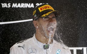 British driver Lewis Hamilton celebrates on the podium at the Yas Marina circuit in Abu Dhabi.