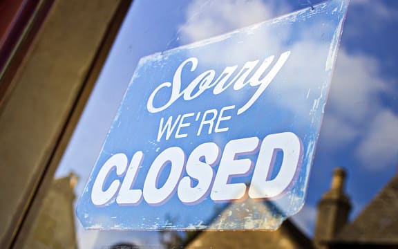 A closed sign hanging in the glass doorway of a shop in the UK