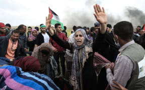 Palestinian protesters wave their national flag and gesture during a demonstration commemorating Land Day near the border with Israel, east of Khan Yunis, in the southern Gaza Strip.