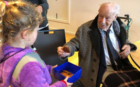 Madison Webb baked Anzac biscuits for veterans at the RSA in Christchurch.
After the dawn service she gives one to 106-year-old veteran, sergeant Bill Mitchell, who fought in the Pacific during his time in the defence force.